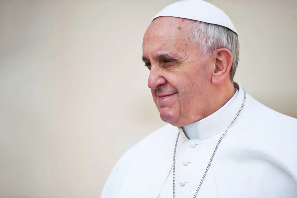 Papa Francesco sorridente guarda rivolto verso sinistra